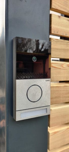 Moderne Gira Türsprechanlage mit integrierter Kamera an einem Metallpfosten im Außenbereich