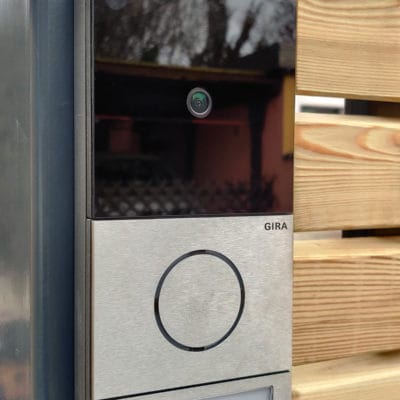 Moderne Gira Türsprechanlage mit integrierter Kamera an einem Metallpfosten im Außenbereich