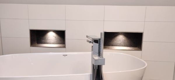 Modernes Bad mit freistehender Wanne; zwei von SHI Gebäudetechnik beleuchtete Wandnischen mit warmweißen LED-Spots.