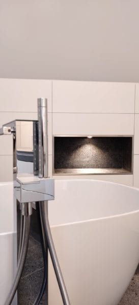 Modernes Bad mit freistehender Wanne; zwei von SHI Gebäudetechnik beleuchtete Wandnischen mit warmweißen LED-Spots.