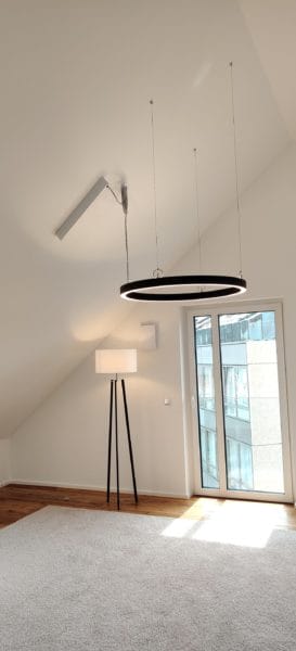 Große runde LED-Pendelleuchte mit Lichtschiene im Dachgeschoss, installiert von SHI Gebäudetechnik.