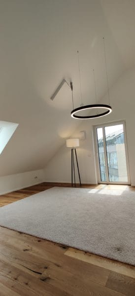 Große runde LED-Pendelleuchte mit Lichtschiene im Dachgeschoss, installiert von SHI Gebäudetechnik.