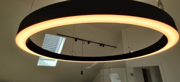 Große runde LED-Pendelleuchte mit Lichtschiene im Dachgeschoss, installiert von SHI Gebäudetechnik.