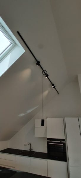 Moderne Dachgeschossküche im Humboldt Palais mit Lichtschiene und Kochinsel, realisiert von SHI Gebäudetechnik.