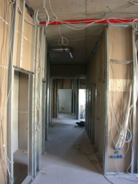 Flur im Praxisumbau mit Trockenbauprofilen, vorgezogenen Leitungen und roter Brandschutzleitung