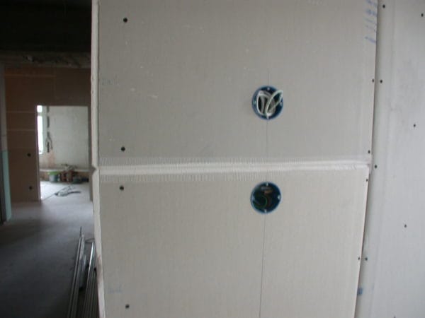 Trockenbauwand mit zwei runden Installationsdosen und herausgeführten Leitungen in Arztpraxis