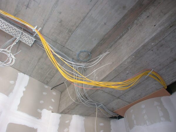 Elektroinstallation an Betondecke mit Kabeltrasse und gelben/ grauen Kabelbündeln in Arztpraxis