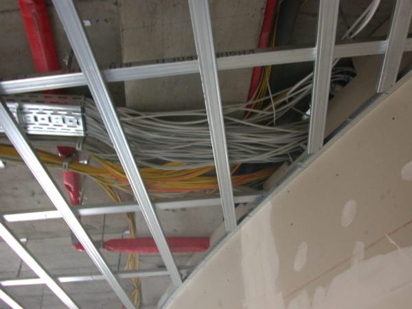 Deckenunterkonstruktion mit Kabeltrassen, Kabelbündeln und roten Brandschutzleitungen