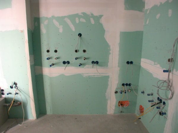 Vorwandinstallation mit grünen Gipskartonplatten, Wasser-/Abwasser- und Elektro-UP-Dosen in einer Arztpraxis