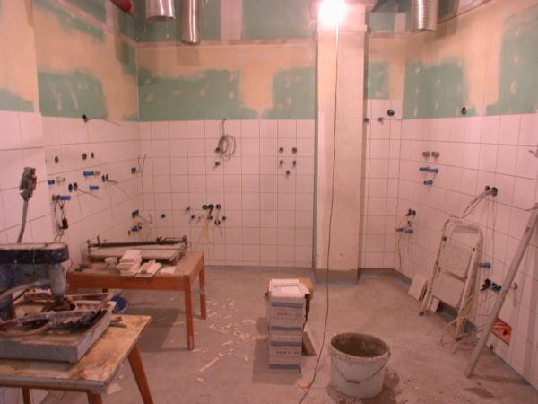 Gefliester Praxisraum im Ausbau mit vielen Dosen, Leitungen und Installationsvorbereitung