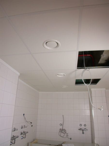 Gefliester Praxisraum mit abgehängter Rasterdecke, runden Lüftungsventilen und herausgeführten Elektrokabeln