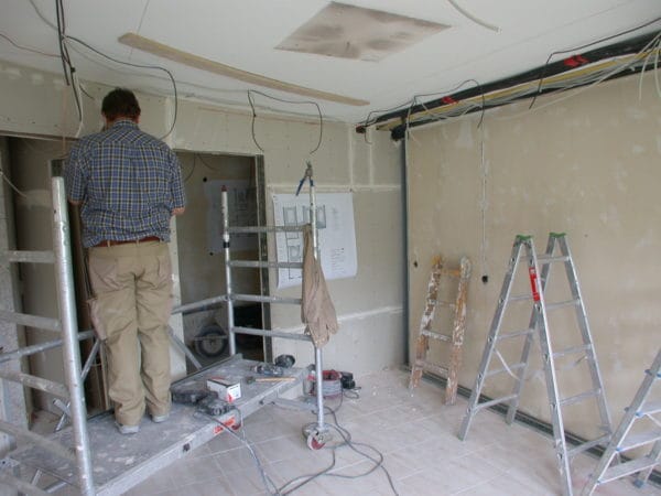 Monteur auf Rollgerüst bei Elektro- und Lichtinstallation; offene Deckenverkabelung in der Praxis Dr. Naumann