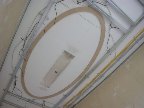 Ovale Deckenunterkonstruktion mit geführten Leitungen und Leuchtenausschnitt in der Praxis Dr. Naumann