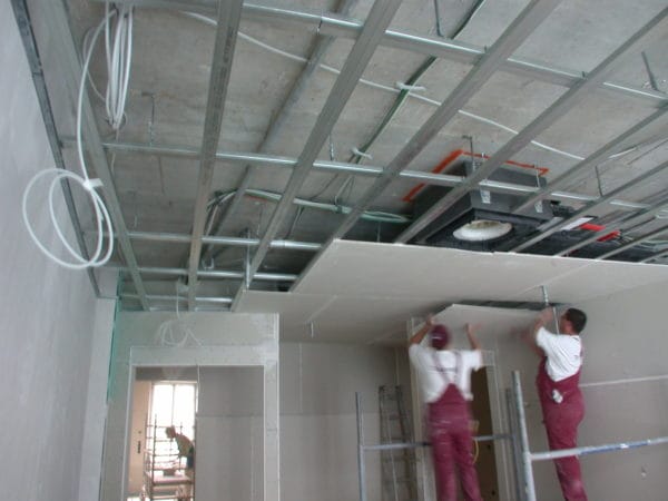 Handwerker montieren eine abgehängte Decke mit Elektro- und Beleuchtungsvorbereitung in der Frauenarztpraxis 5 Höfe München