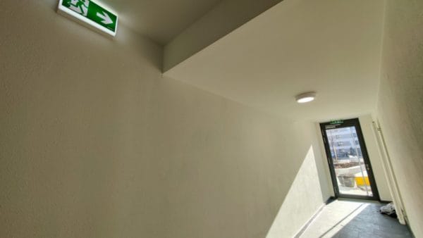 Rettungszeichenleuchte und Sicherheitsbeleuchtung im Flur der Wohnanlage ANTON in Augsburg – SHI Elektro