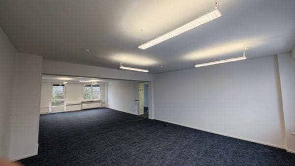 Büroraum leer mit weißen Wänden, Teppichboden und Bürolampen