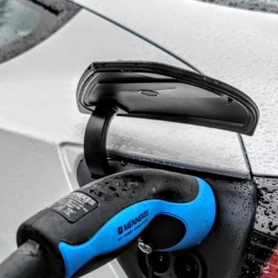Ladebuchse mit Stecker beim Laden bei weißem Tesla