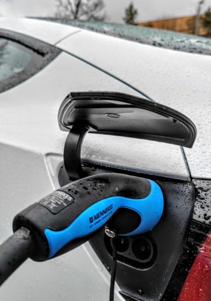 Ladebuchse mit Stecker beim Laden bei weißem Tesla