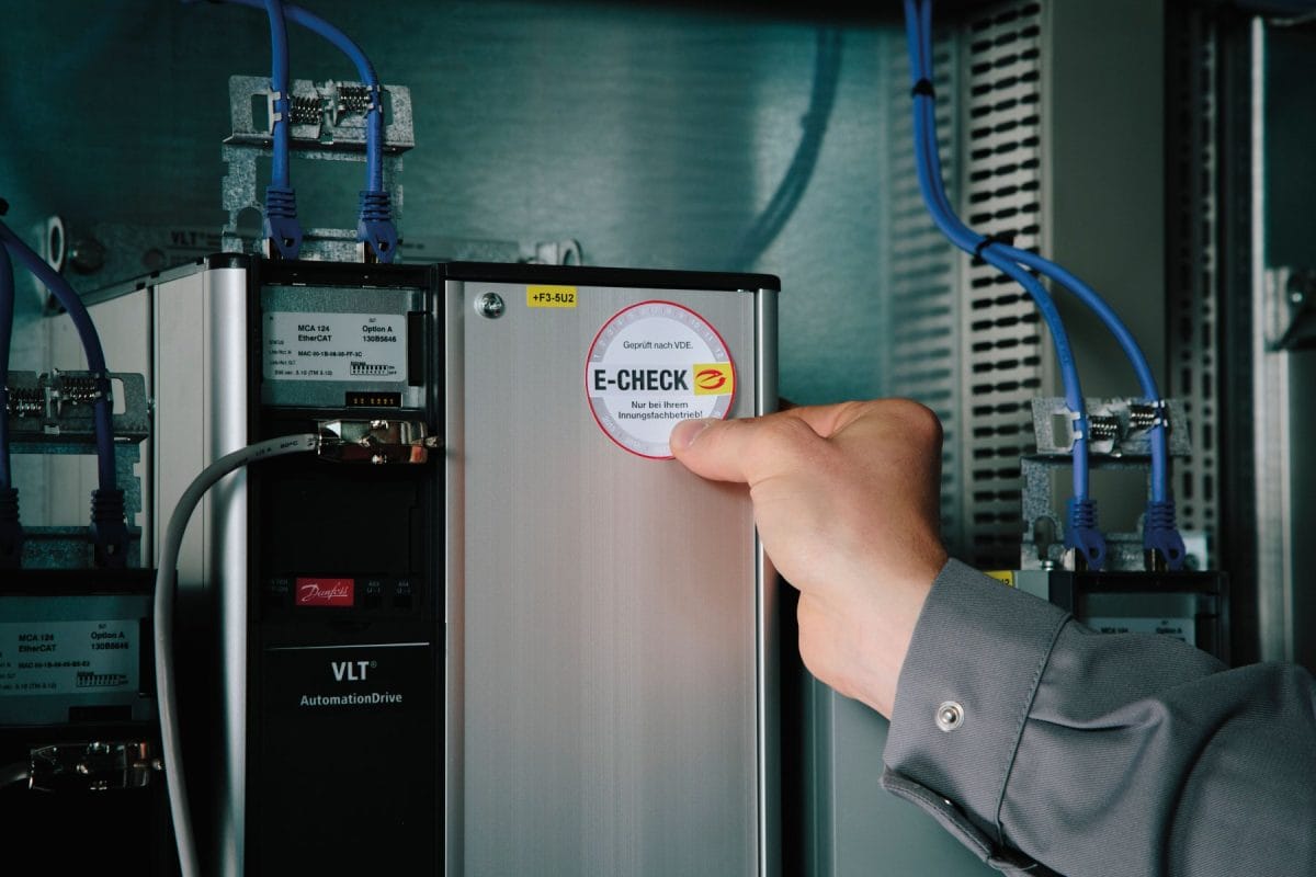 Prüfsiegel E-Check auf Elektronikkasten mit Kabeln im Hintergrund