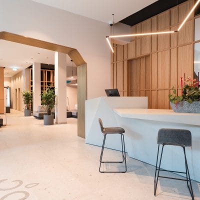 Moderner Empfangsbereich mit Design-Rezeption, Sitzgelegenheiten und Beleuchtung im Hotel Zeller’s Quartier Königsbrunn – Elektro- und Lichtinstallation von SHI Gebäudetechnik GmbH