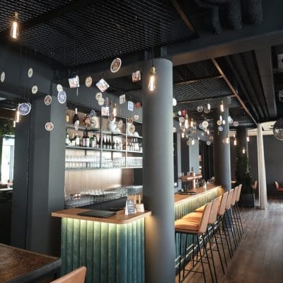 Moderne Bar im Hotel Zeller Königsbrunn mit LED-Akzentbeleuchtung und Edison-Leuchten, realisiert durch SHI Gebäudetechnik GmbH