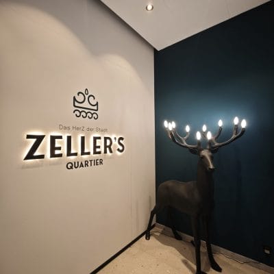Eingangsbereich im Zeller's Quartier Königsbrunn mit indirekter Logo-Beleuchtung und Design-Leuchte in Hirschform