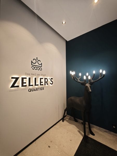 Eingangsbereich im Zeller's Quartier Königsbrunn mit indirekter Logo-Beleuchtung und Design-Leuchte in Hirschform