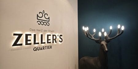 Eingangsbereich im Zeller's Quartier Königsbrunn mit indirekter Logo-Beleuchtung und Design-Leuchte in Hirschform
