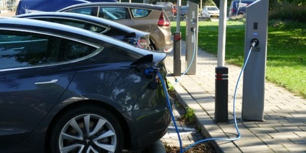 Schwarzer Tesla steht geparkt an einer E-Ladestation und wird geladen